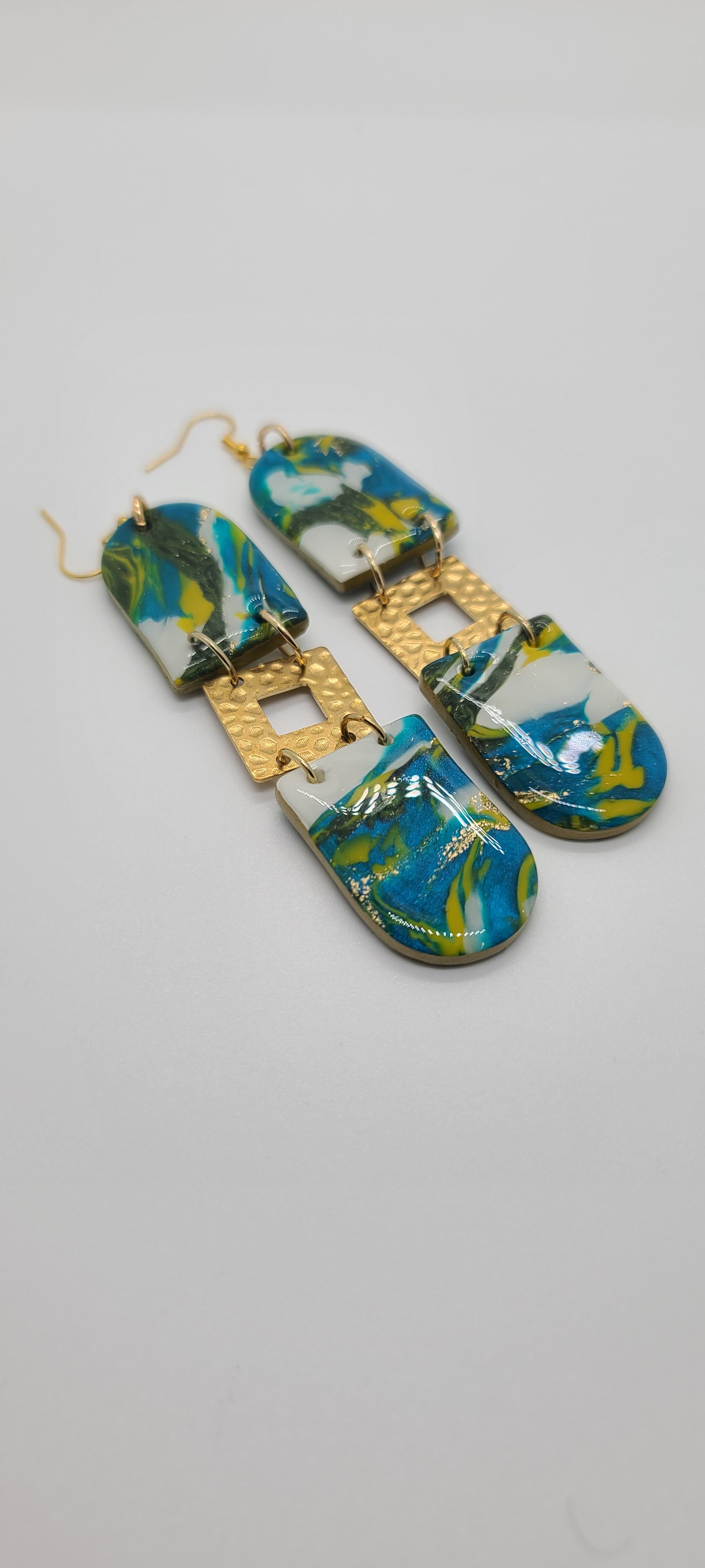 Length: 4.5 inches | Weight: 0.8 ounces  Distinctly You! These earrings are made with U-shape polymer clay in aqua yellow gold white green, and gold squared hammered charms.