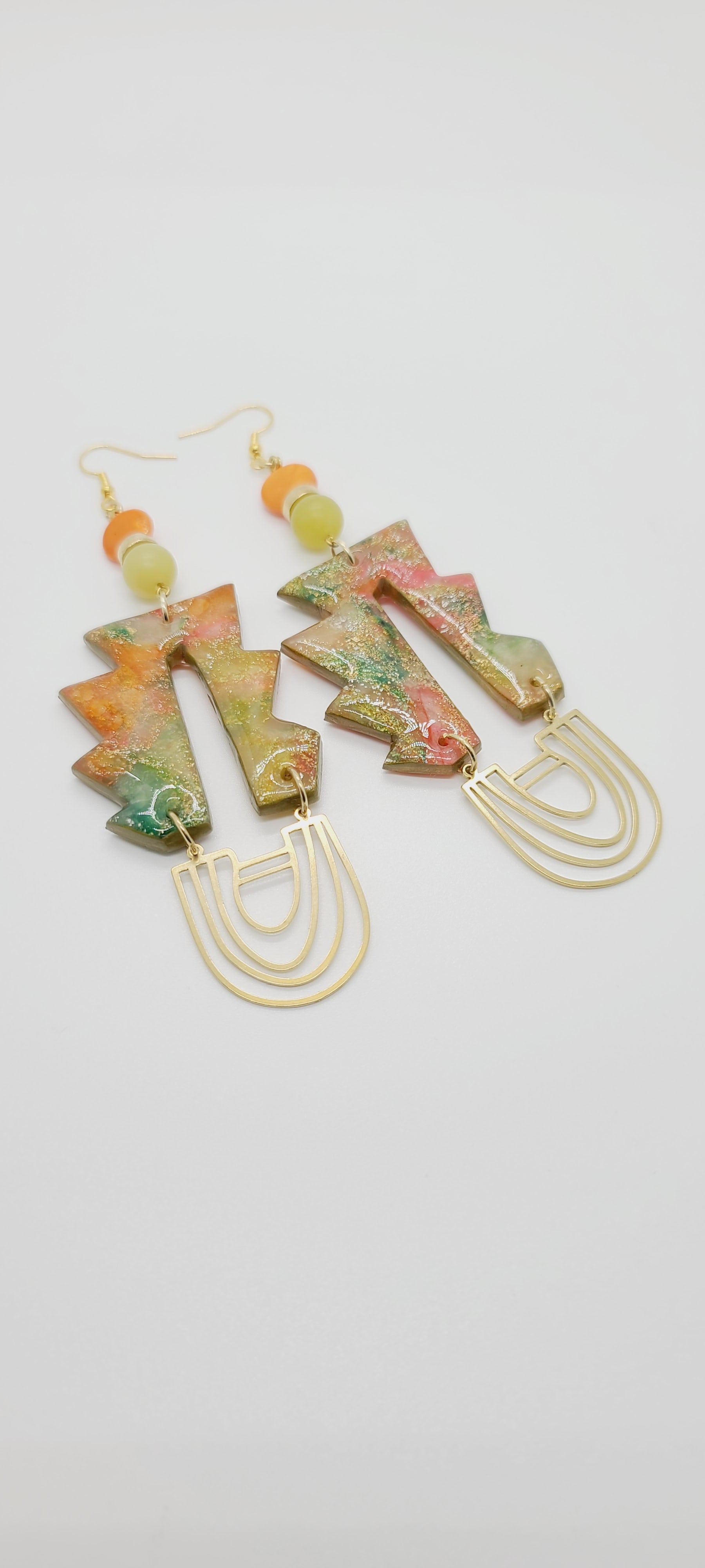 Length: 5 inches | Weight: 0.9 ounces  Distinctly You! These earrings are made with geometric-shape polymer clay in orange green gold with gold flake, U-shape gold charms,10mm frosted green glass beads, 8mm orange glass discs, and gold rondelles.