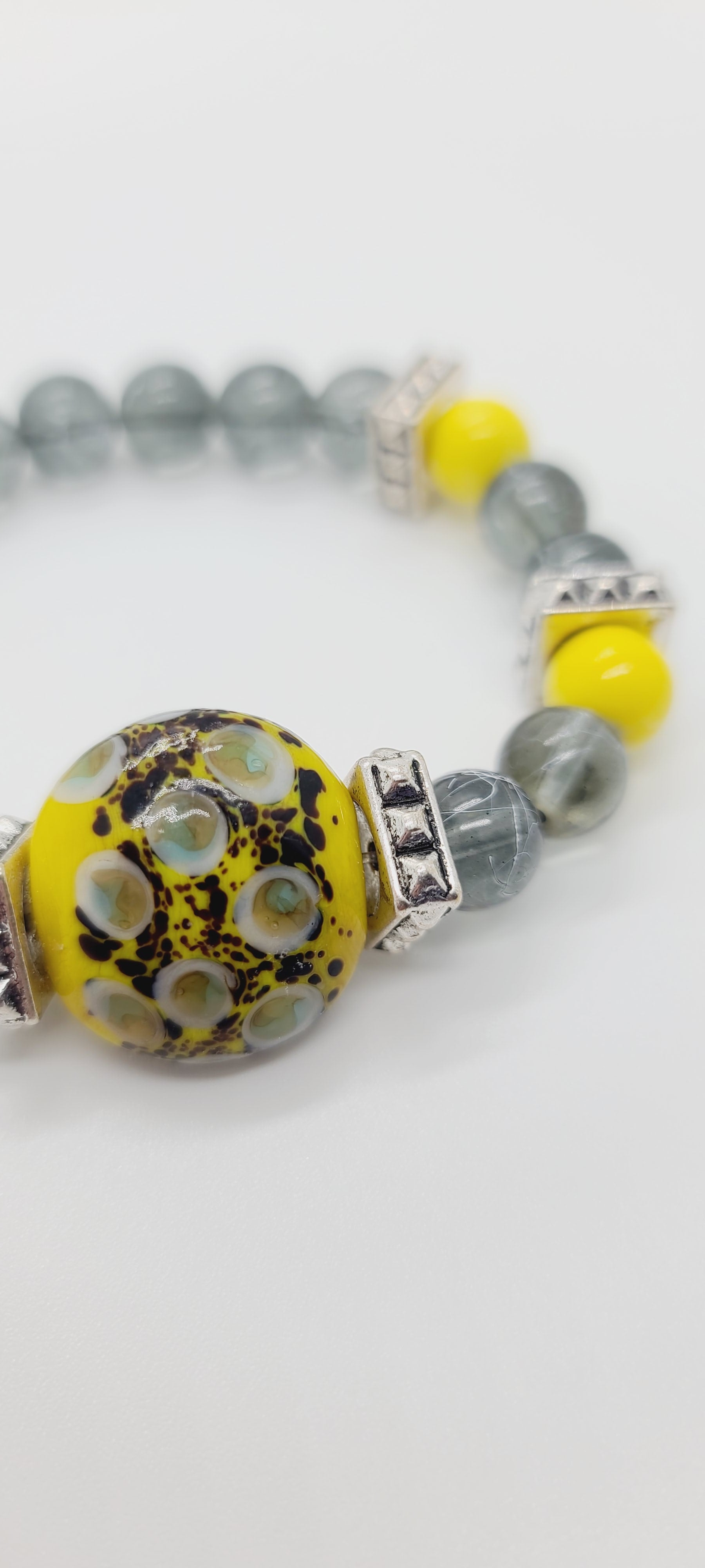 Length: 7.75 inches | Weight: 1.8 ounces  Distinctly You! This bracelet is made with 10mm yellow ceramic and grey white painted glass beads, accented with chrome square spacers, grey and yellow speckle ceramic center charm.