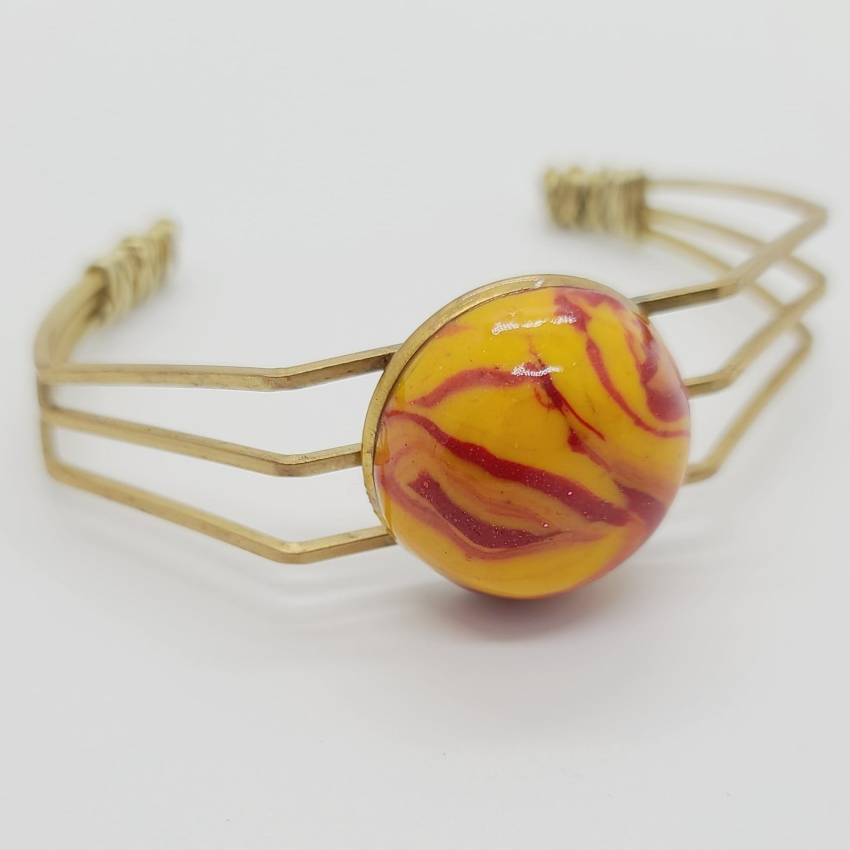 Length: 6.75 inches | Weight: 0.6 ounces  Distinctly You! This brass metal bracelet is made with red and gold swirl polymer clay stone covered in resin.