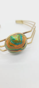 Length: 6.75 inches | Weight: 0.6 ounces  Distinctly You! This brass metal bracelet is made with multi-colored green, orange, gold swirl polymer clay stone covered in resin.