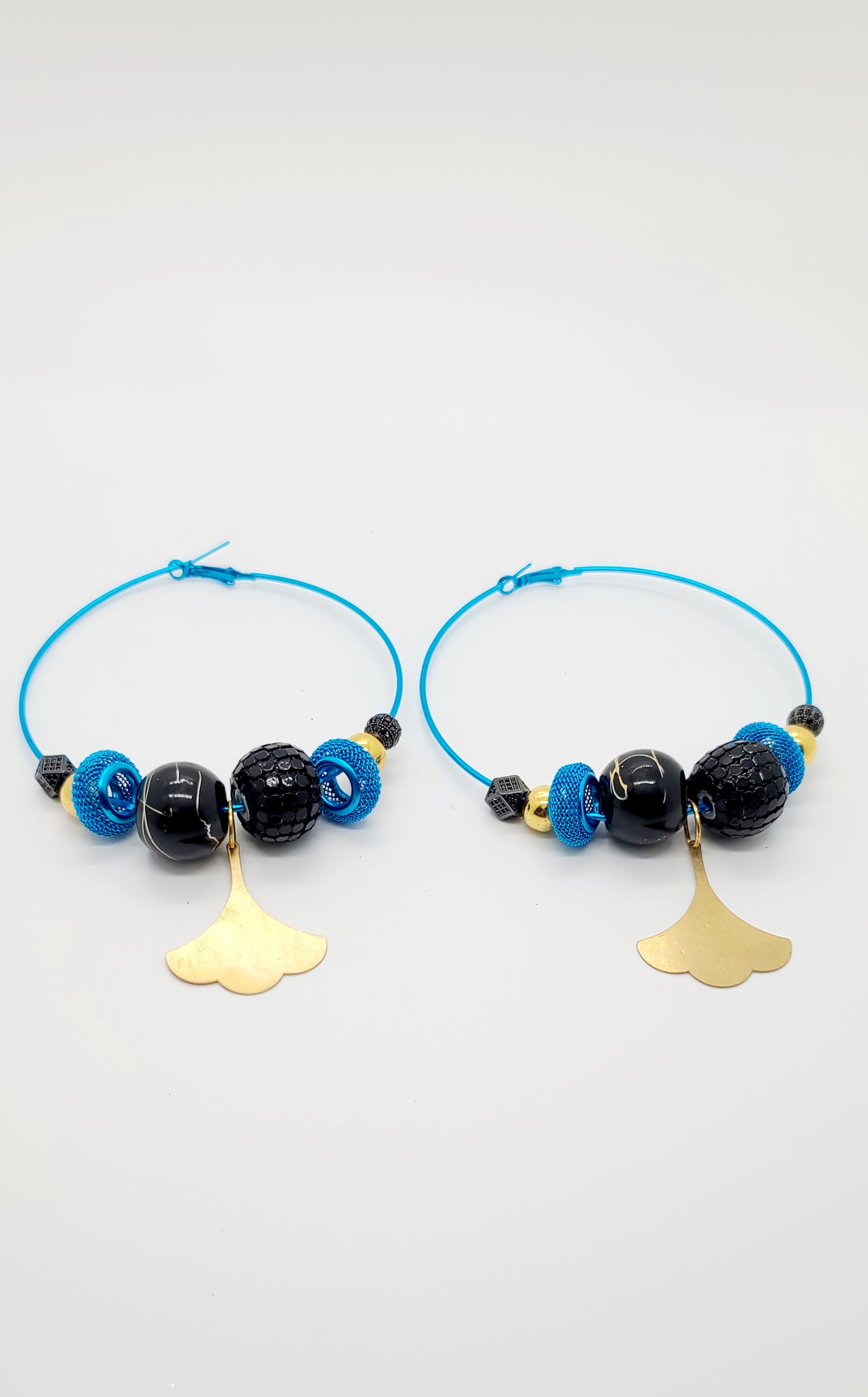Length: 3.5x3.5 inches | Weight: 1.6 ounces  Distinctly You! These earrings are made with large blue hoops, 15mm black wooden beads, 15mm sequin beads, blue mesh rondelle, 10mm gold resin beads, 8mm black disco balls, and brass floral charm.