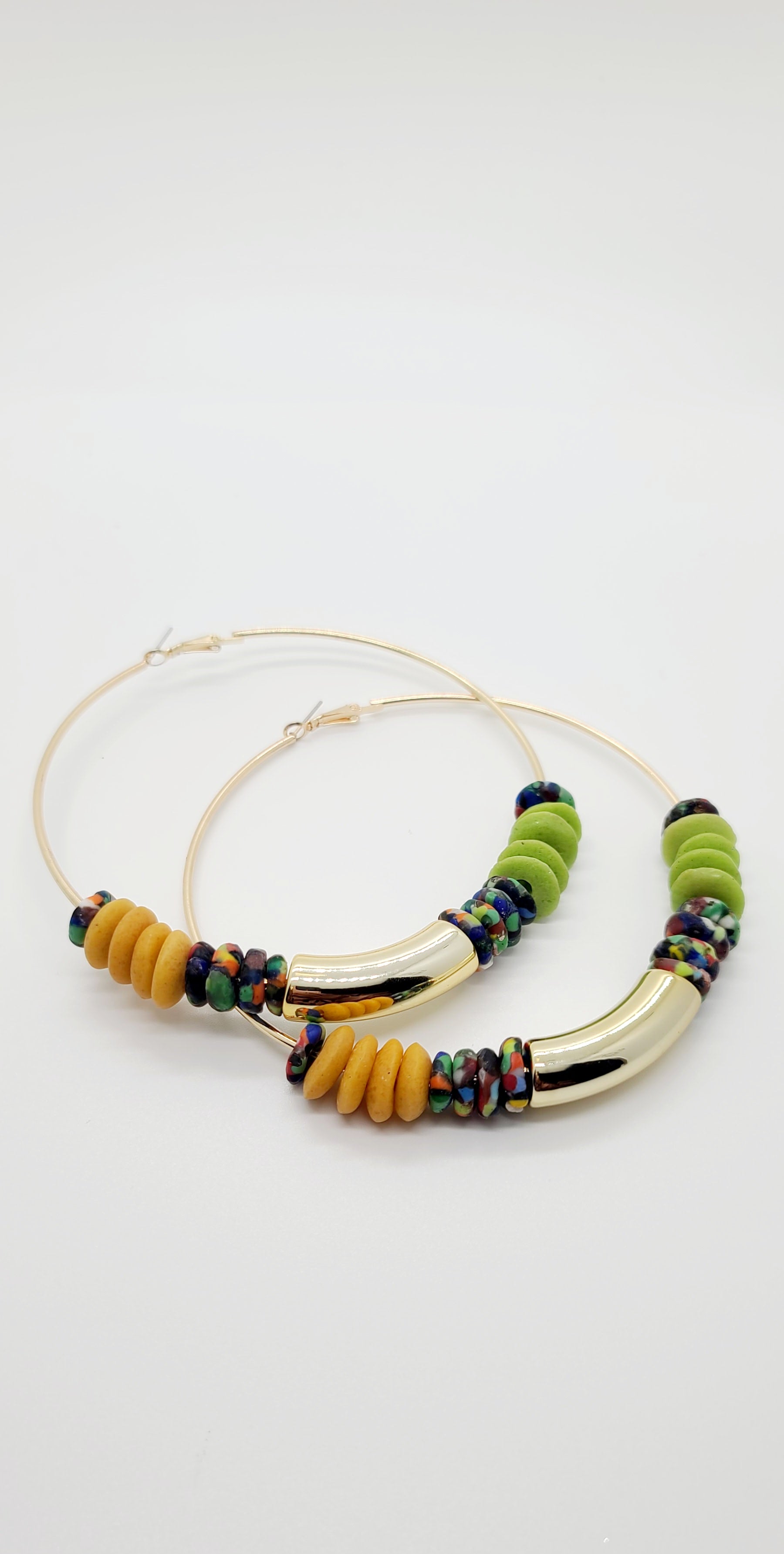 Length: 4x4 inches | Weight: 1.9 ounces  Distinctly You! These earrings are made with large gold Hoops, gold, green, multi-colored print Ashanti glass saucers, and curved gold resin charm.