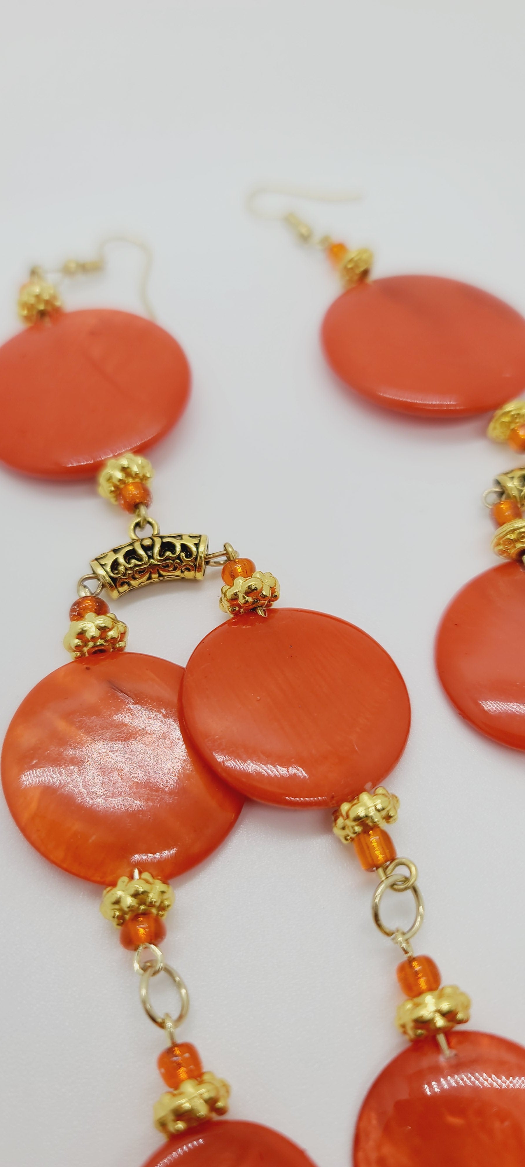 Length: 10 inches | Weight: 2.4 ounces  Distinctly You! These earrings are made with orange glass circular disc, orange tassels, accented with gold spacers, orange glass seed beads, and gold bail.