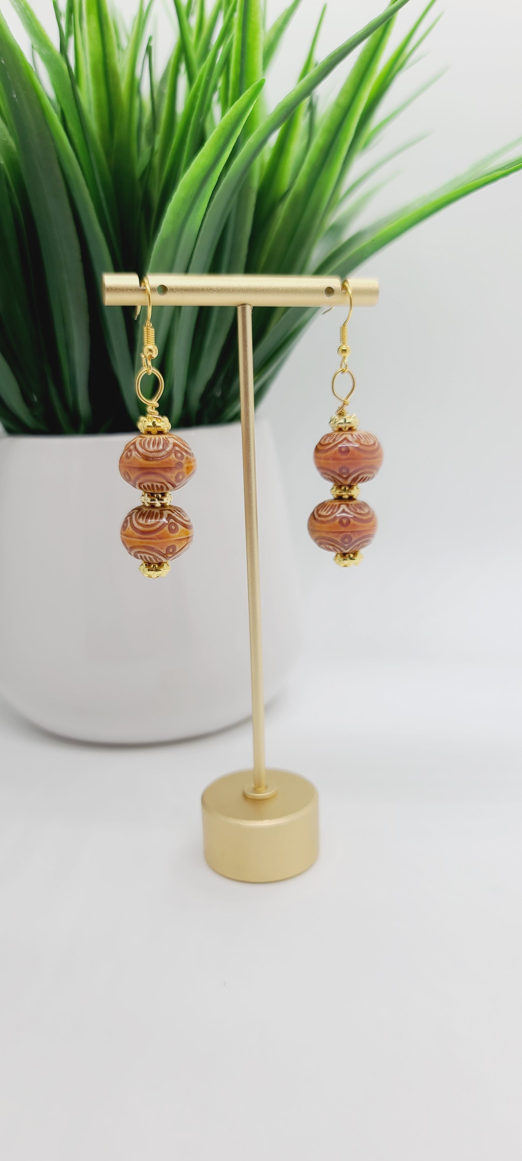 Length: 2.5 inches | Weight: 0.7 ounces  Distinctly You! These earrings are made with ethnic print mauve wood, covered with resin, and gold rondelles.