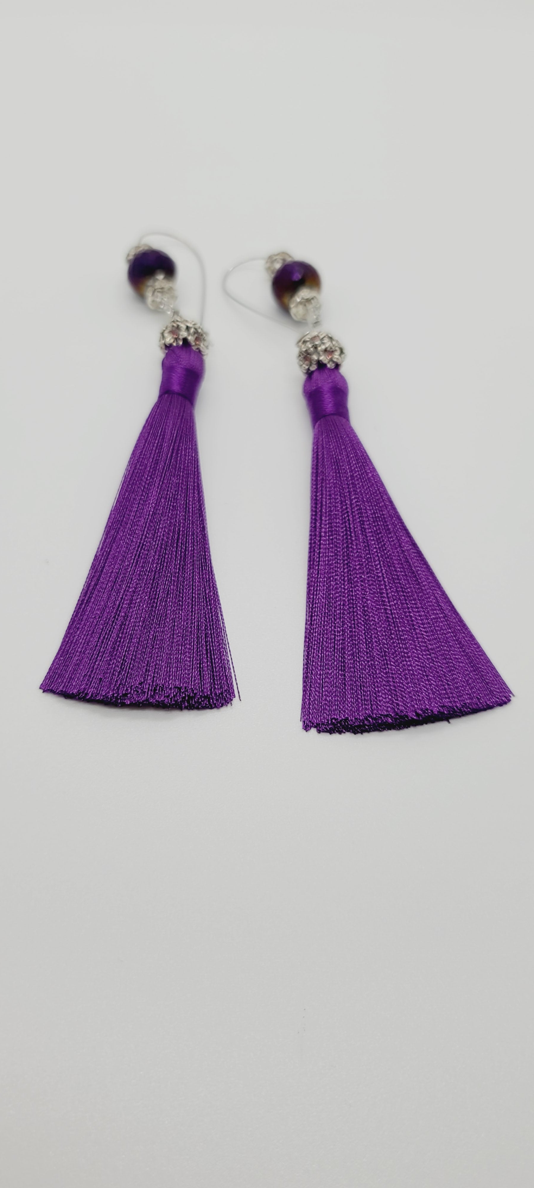 Length: 5 inches | Weight: 0.5 ounces  Distinctly You! These earrings are made with purple tassels, 10mm purple faceted glass stones, accented with silver and purple rondelles.