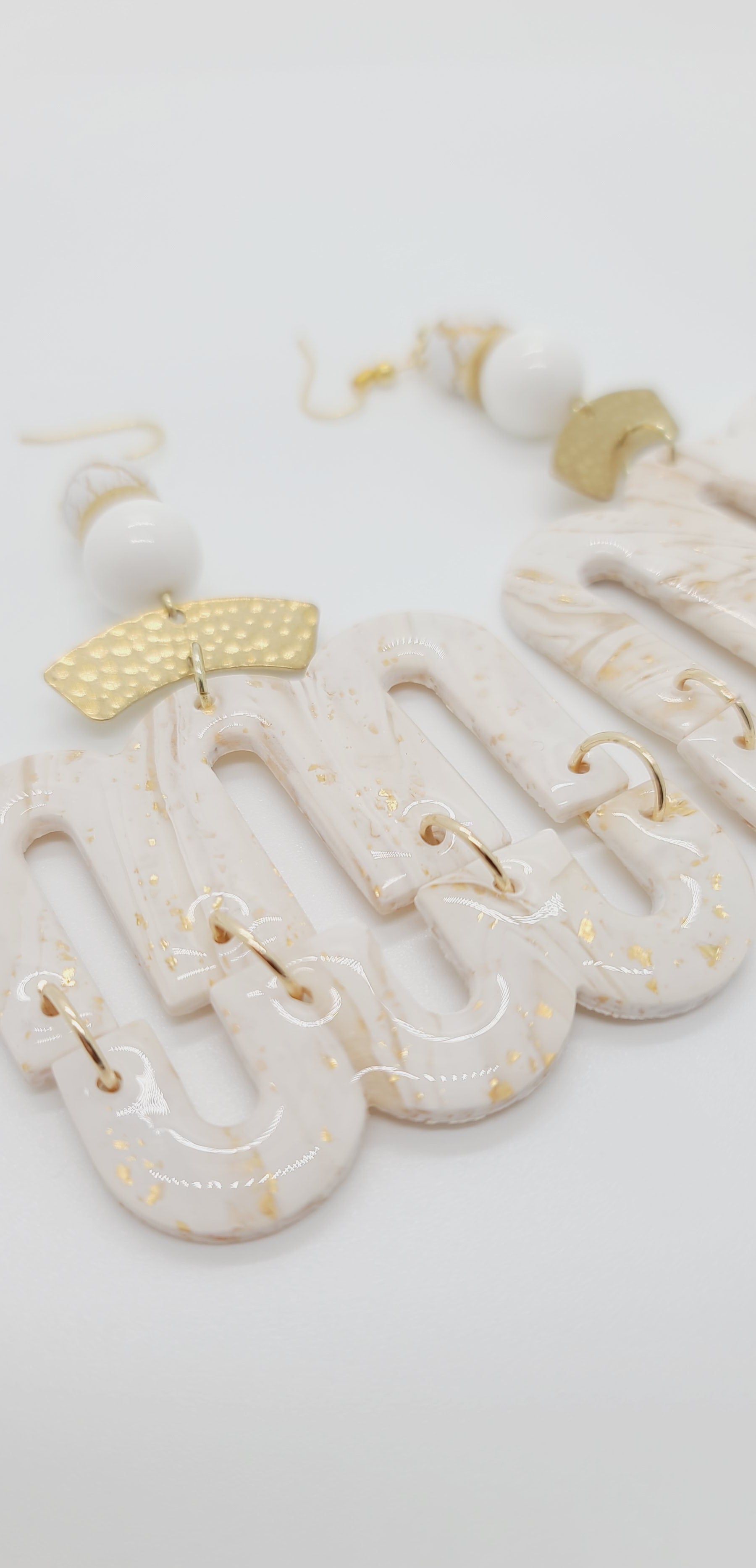 Length: 4 inches | Weight: 1.3 ounces  Distinctly You! These earrings are made with white and gold polymer clay covered in resin M/U-shape, hammered gold curved charms,10mm glass opaque glass beads, 8mm white and gold matte beads, and gold rondelles.