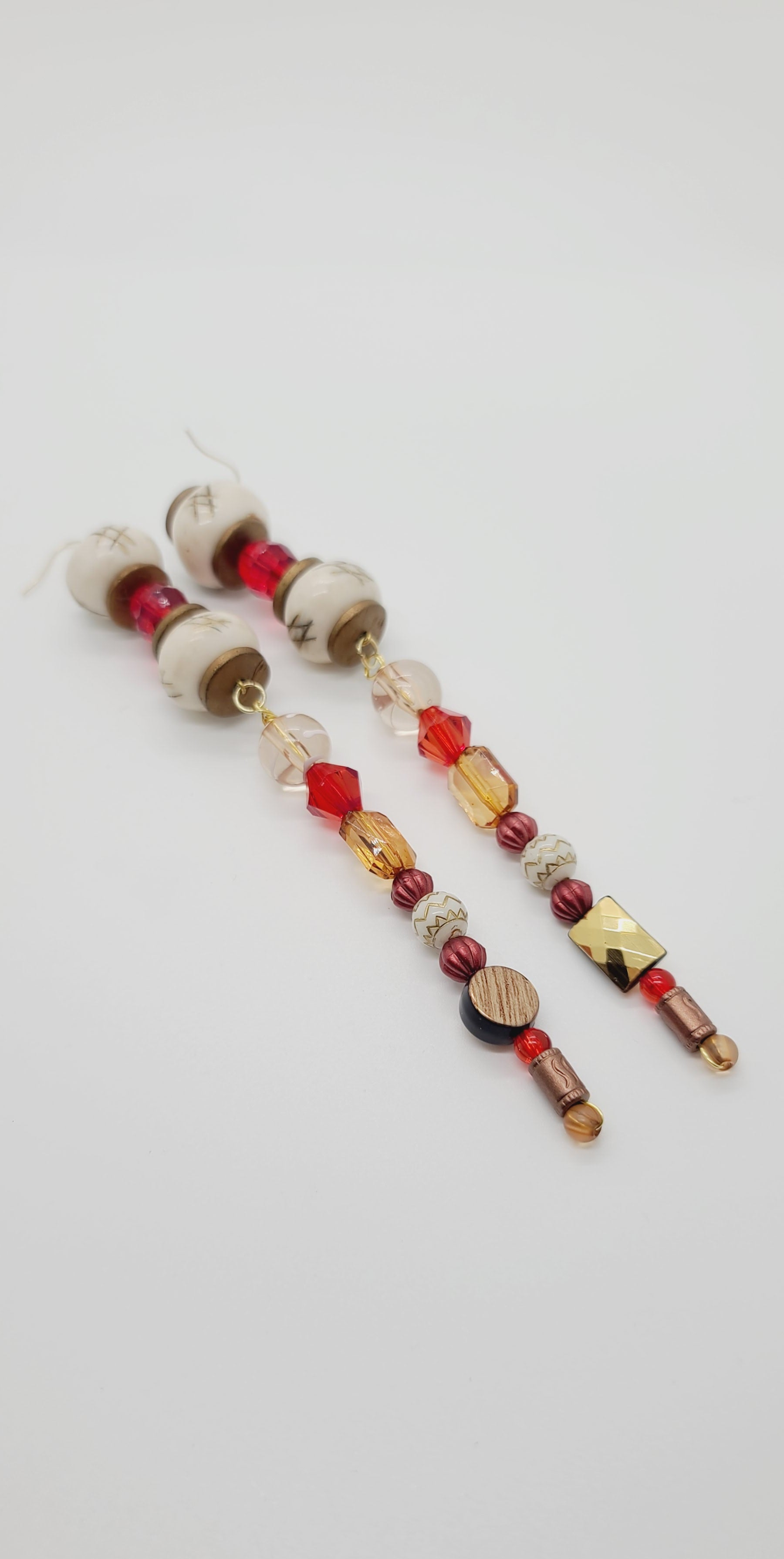 Length: 7 inches | Weight: 1.5 ounces  Distinctly You! These earrings are made with white checked Batik bone beads, gold resin rondelles, 12mm and 10mm red faceted resin beads, 12mm clear and white glass beads, 10mm clear gold emerald cut beads, 6mm copper beads, 8mm gold carved white beads, copper spacers, and 4mm red and tan beads.