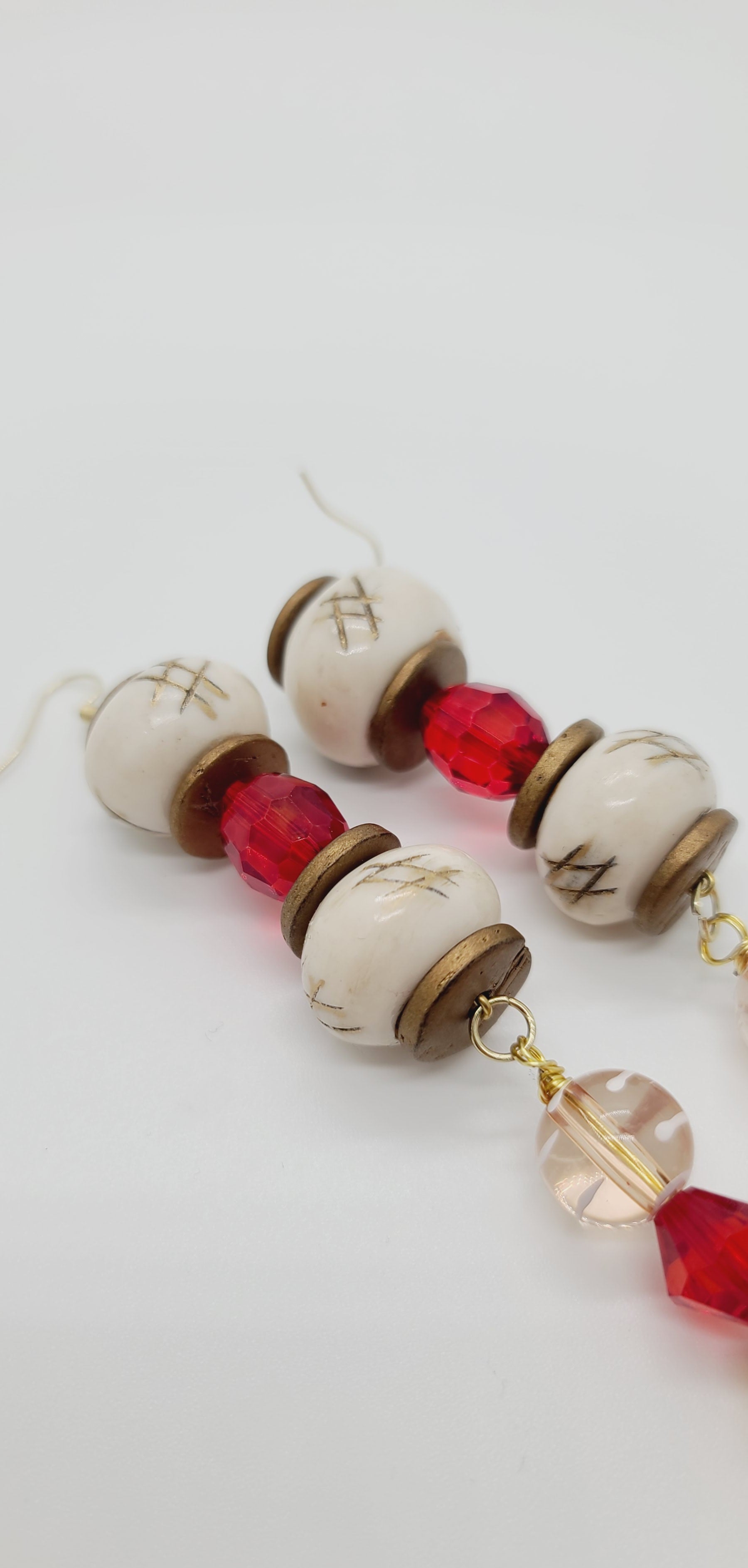Length: 7 inches | Weight: 1.5 ounces  Distinctly You! These earrings are made with white checked Batik bone beads, gold resin rondelles, 12mm and 10mm red faceted resin beads, 12mm clear and white glass beads, 10mm clear gold emerald cut beads, 6mm copper beads, 8mm gold carved white beads, copper spacers, and 4mm red and tan beads.