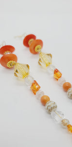 Length: 6 inches | Weight: 1.1 ounces  Distinctly You! These earrings are made with orange Ashanti glass saucers, 14mm, 10mm, 8mm pale gold clear orange faceted glass and resin beads, 8mm white gold carved resin covered beads, 4mm clear resin beads, gold beaded rondelles, and 3mm gold beads.