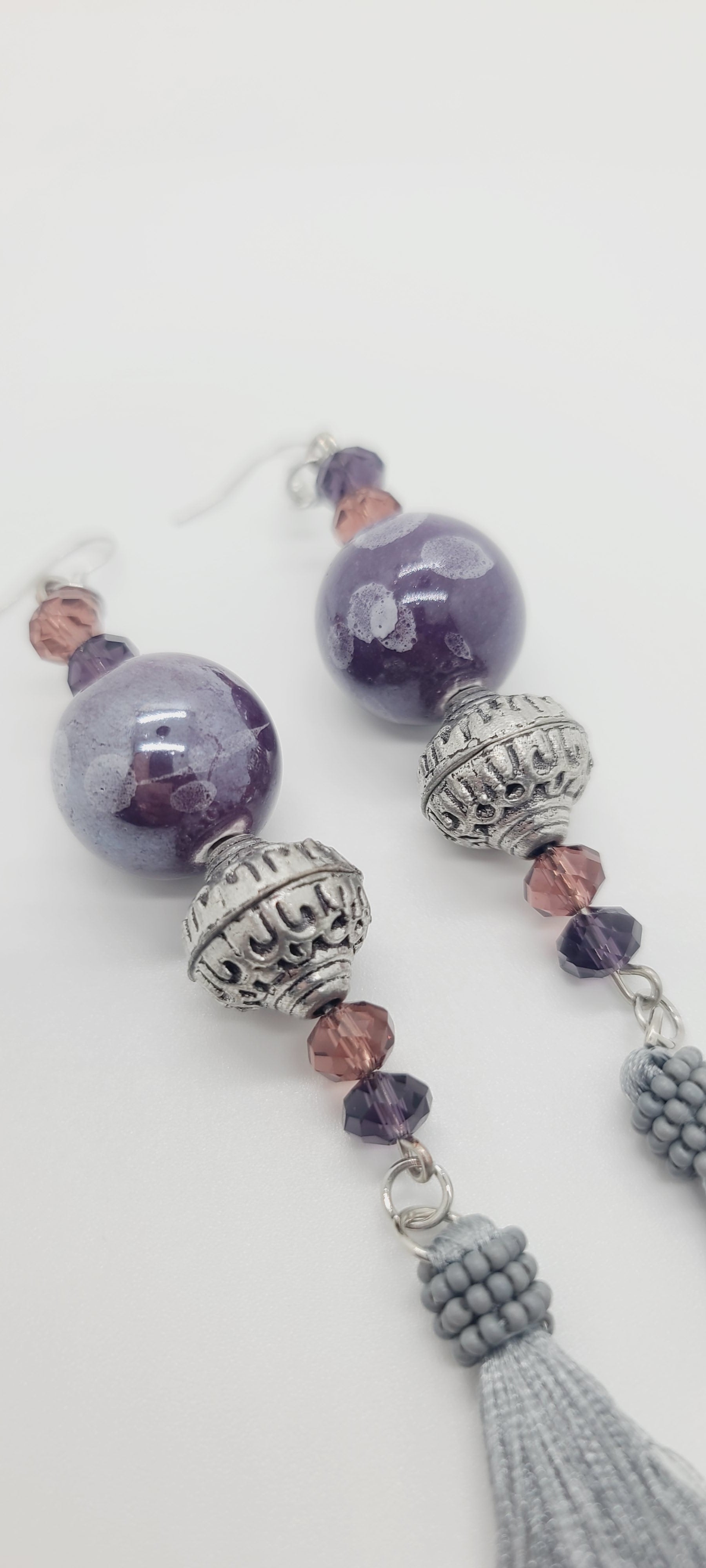 Length: 5 inches | Weight: 1.2 ounces  Distinctly You! These earrings are made with 20mm purple iridescent ceramic stones, 16mm metal lanterns, 6mm purple and pink faceted glass stones, and grey tassels.