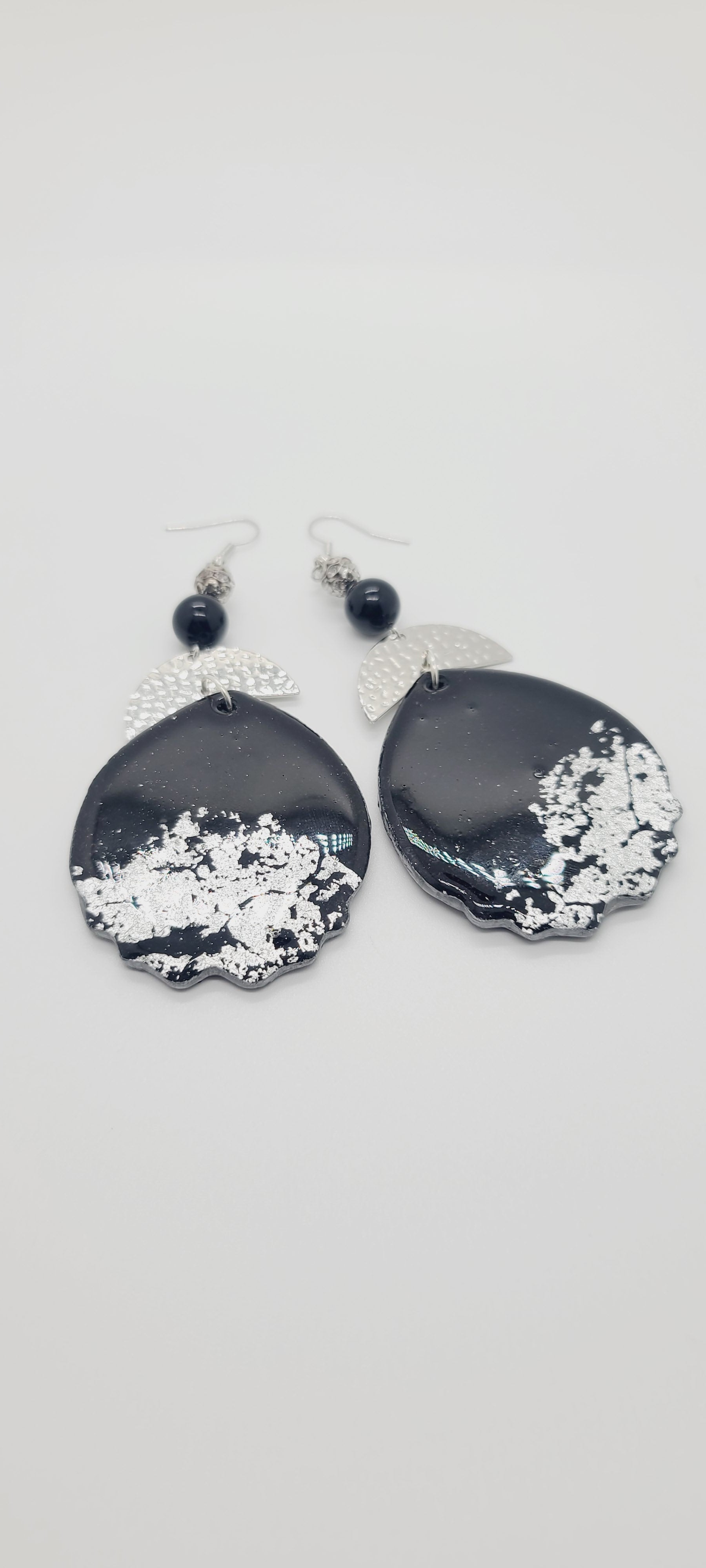 Length: 4 inches | Weight: 1.2 ounces  Distinctly You! These earrings are made with black and silver embossed polymer clay, silver hammered curved charms, and 10mm black Onyx beads, and silver filigree beads.