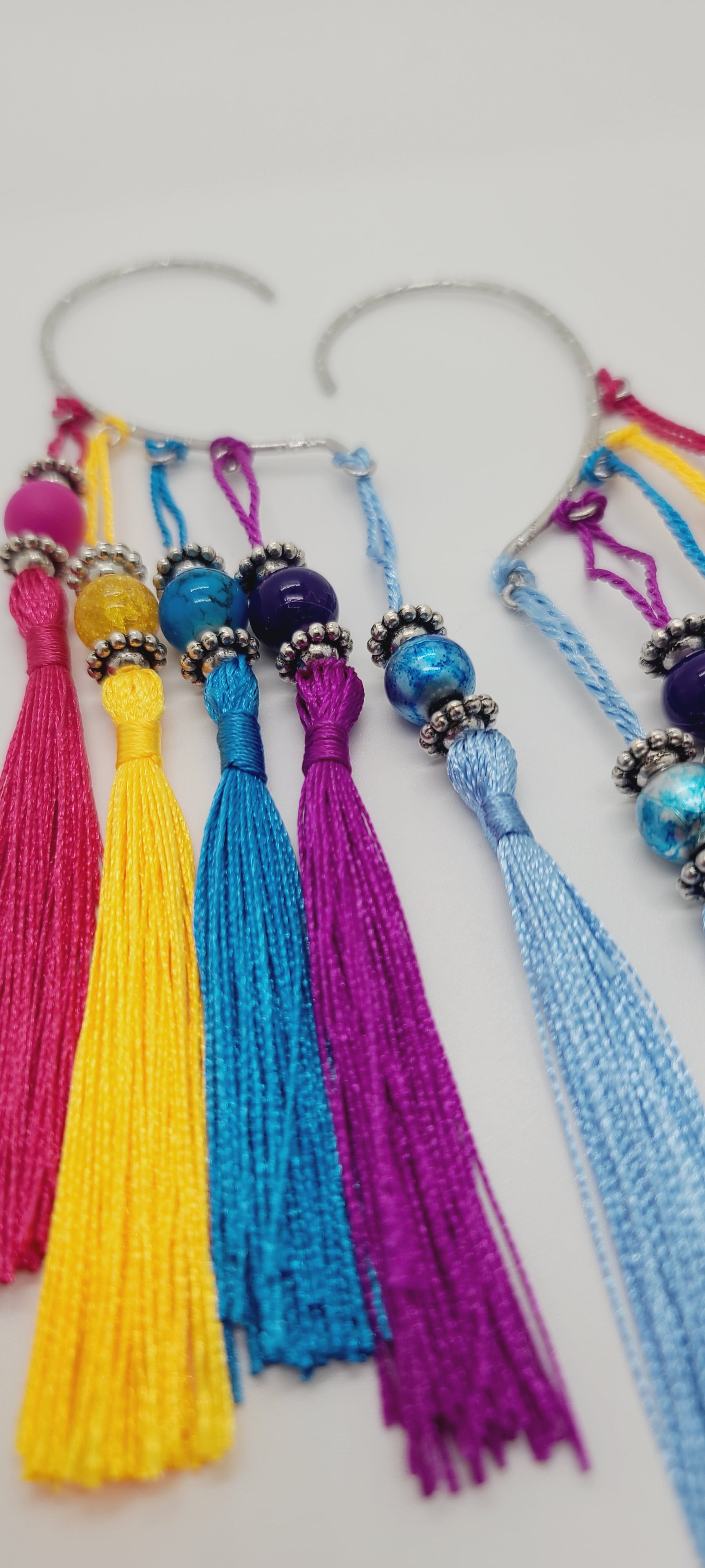Length: 8 inches | Weight: 1.6 ounces  Distinctly You! These silver cuff earrings are made with colorful tassels, matching beads, and silver rondelles.