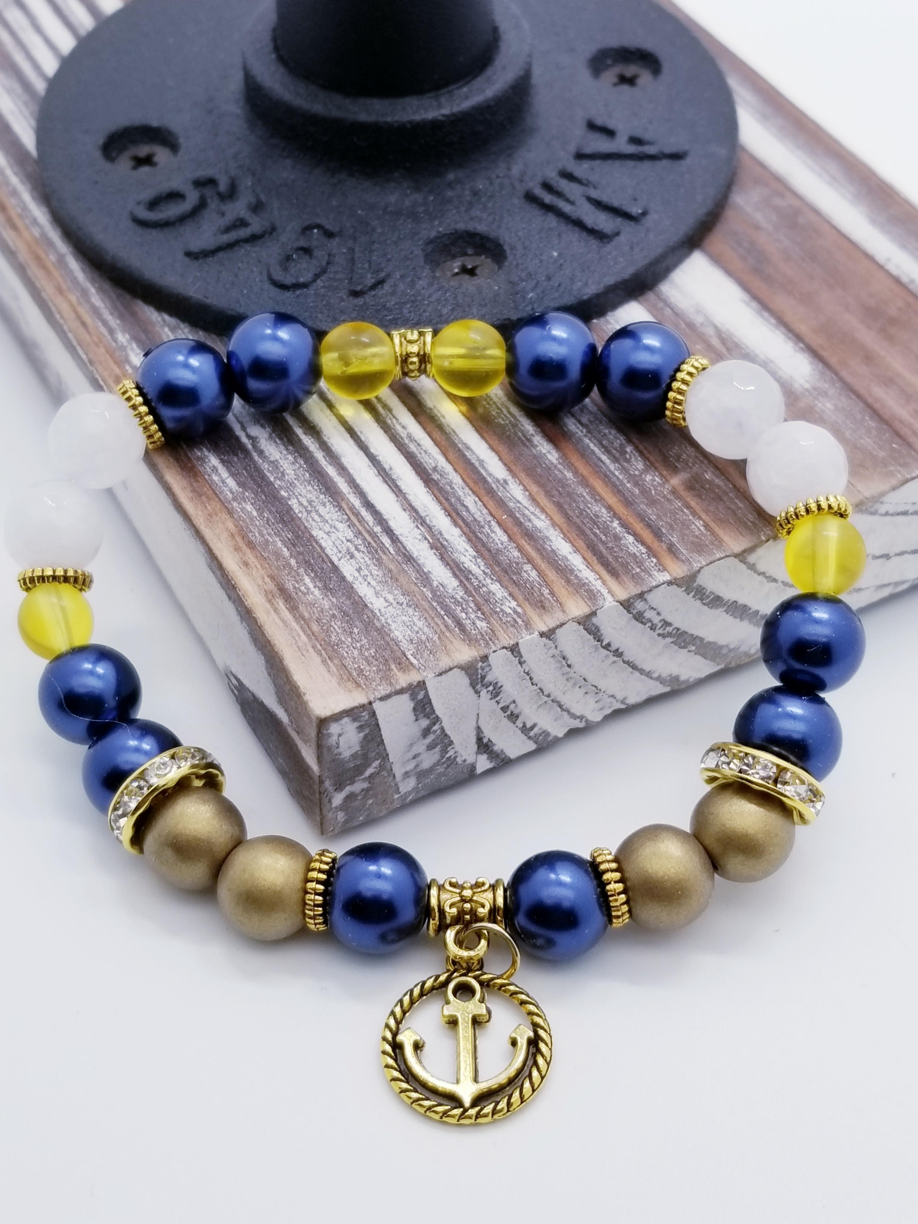 Honor, Courage, and Commitment (US Navy core values) inspired bracelet to honor our troops, veterans, and the families that support them! Anchor charm with white turquoise beads, navy metallic beads, yellow glass beads, gold faceted spacer beads, grade A rondel (gold and white rhinestones), and gold spacers. 