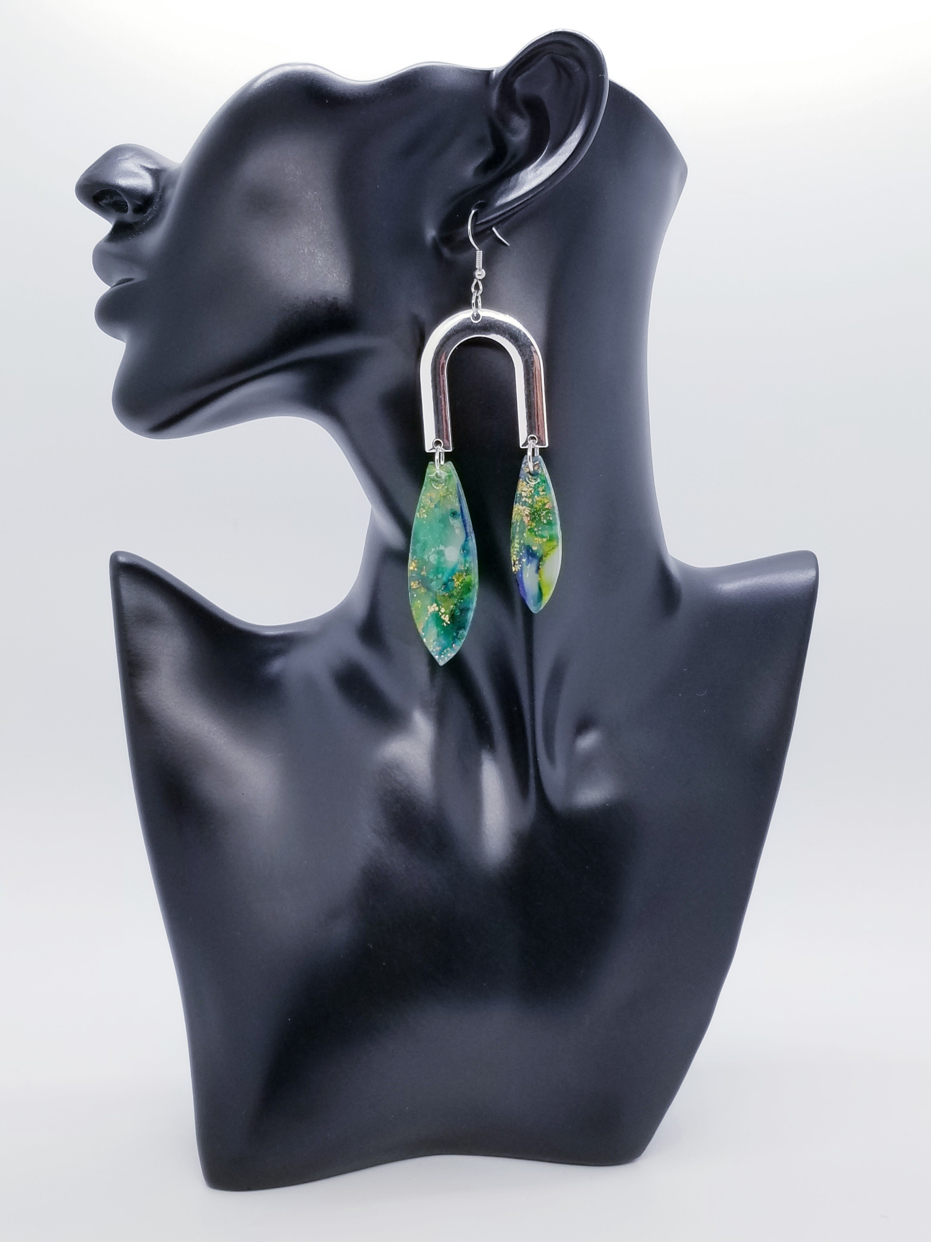 Length: 4 inches | Weight: 0.7 ounces  Distinctly You! The earrings are handmade using green and gold swirl resin design, silver u-shaped charms, and hypoallergenic hooks with back closures. 