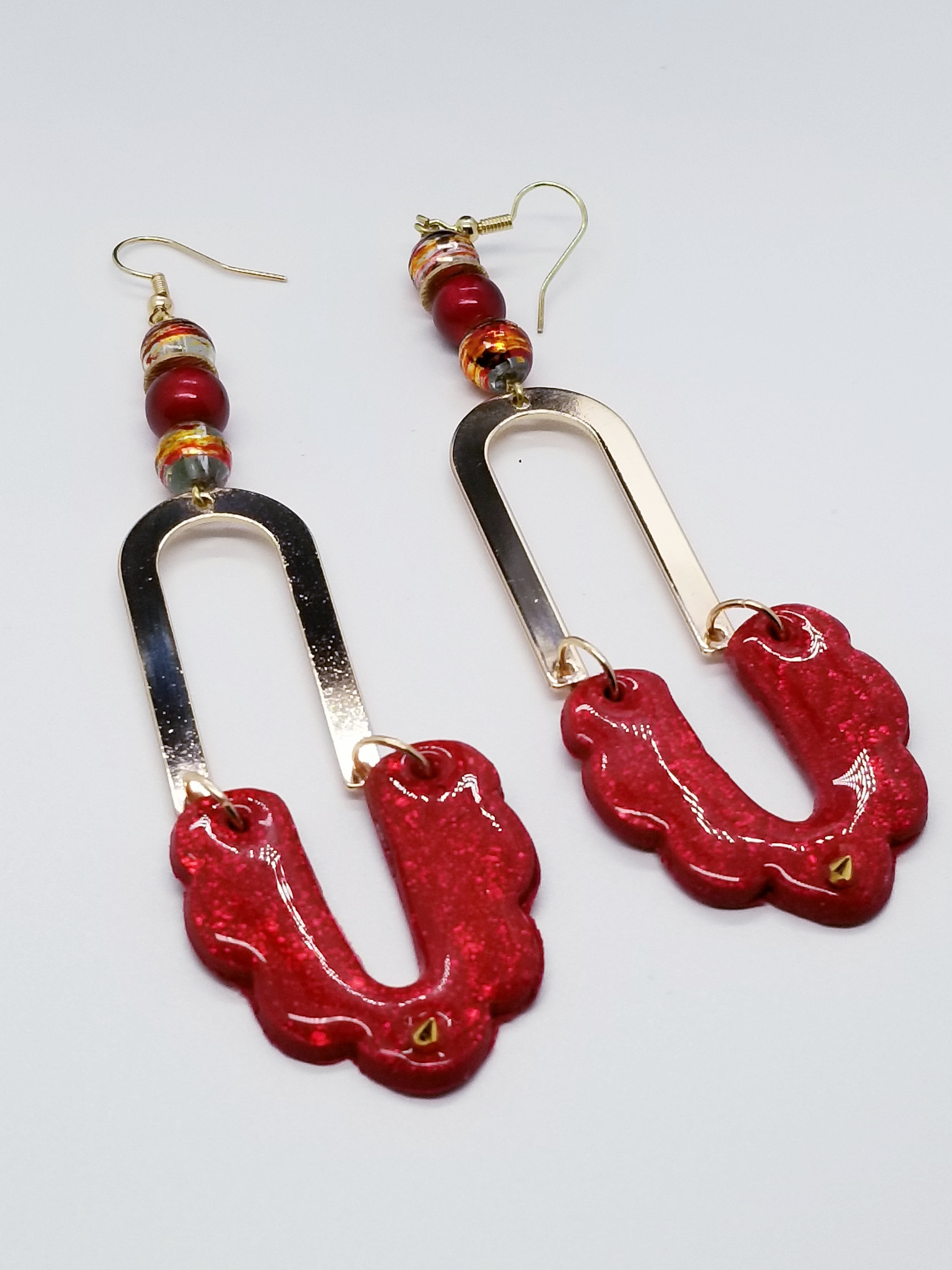 Length: 4.5 inches | Weight: 0.6 ounces  Designed just for you! The earrings are handmade using   red glitter swirl polymer clay scalloped design with resin overlay, gold u-shaped charm, 8mm red and gold swirl glass beads, 8mm red opaque glass beads, gold spikes, gold rondelle spacers, gold head pins, and hypoallergenic hooks with back closures. 