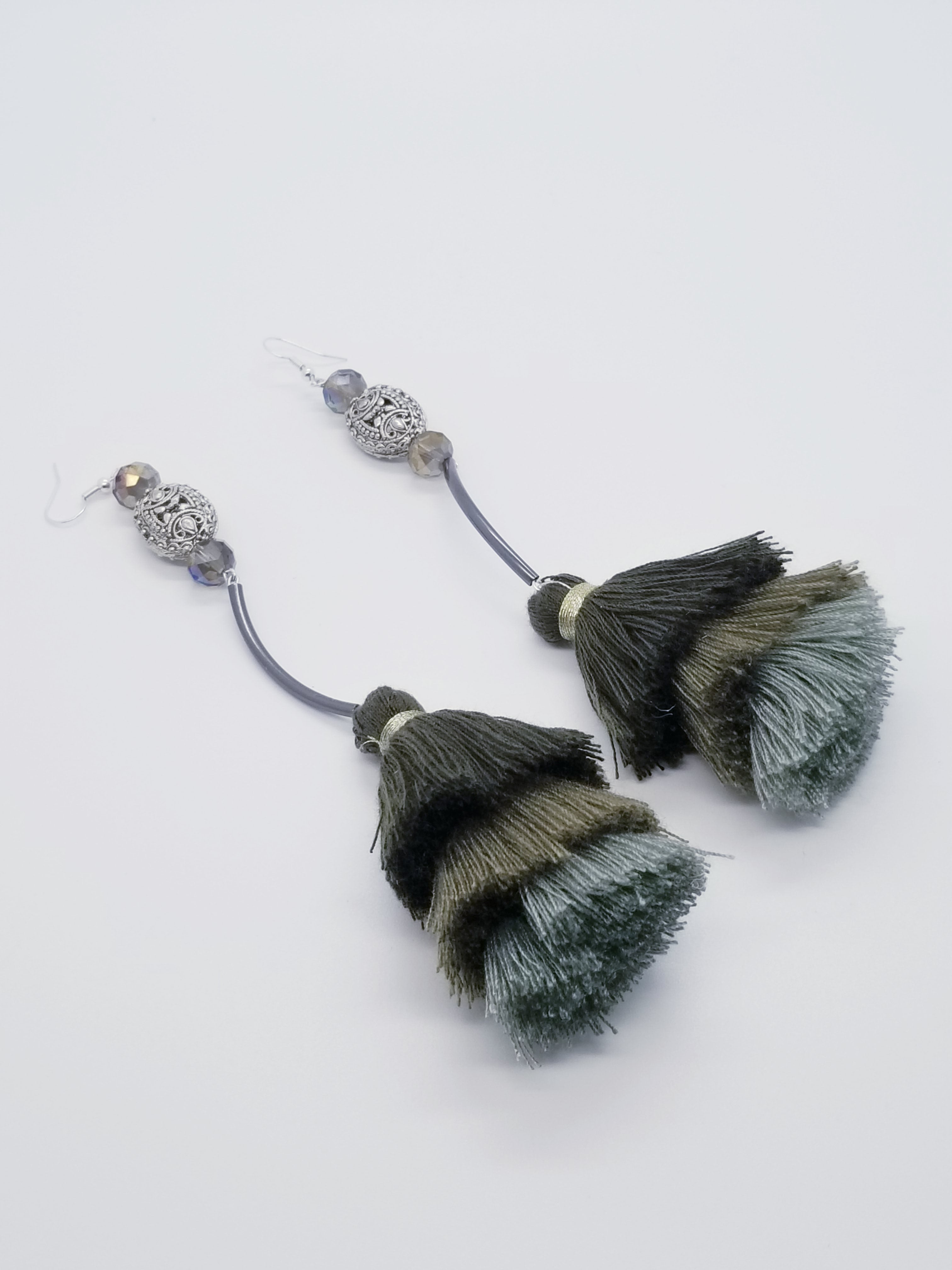 PLEASE BE AWARE: Earrings Hang Past Shoulders  5.5 inches or more  Length: 7 inches | Weight: 1 ounce (earlobe supports provided due to weight)  Designed just for you! The earrings are handmade using black, green, seafoam tassels, black curve tube, 10mm faceted crystal, silver filigree charm, and hypoallergenic hooks with back closures. 